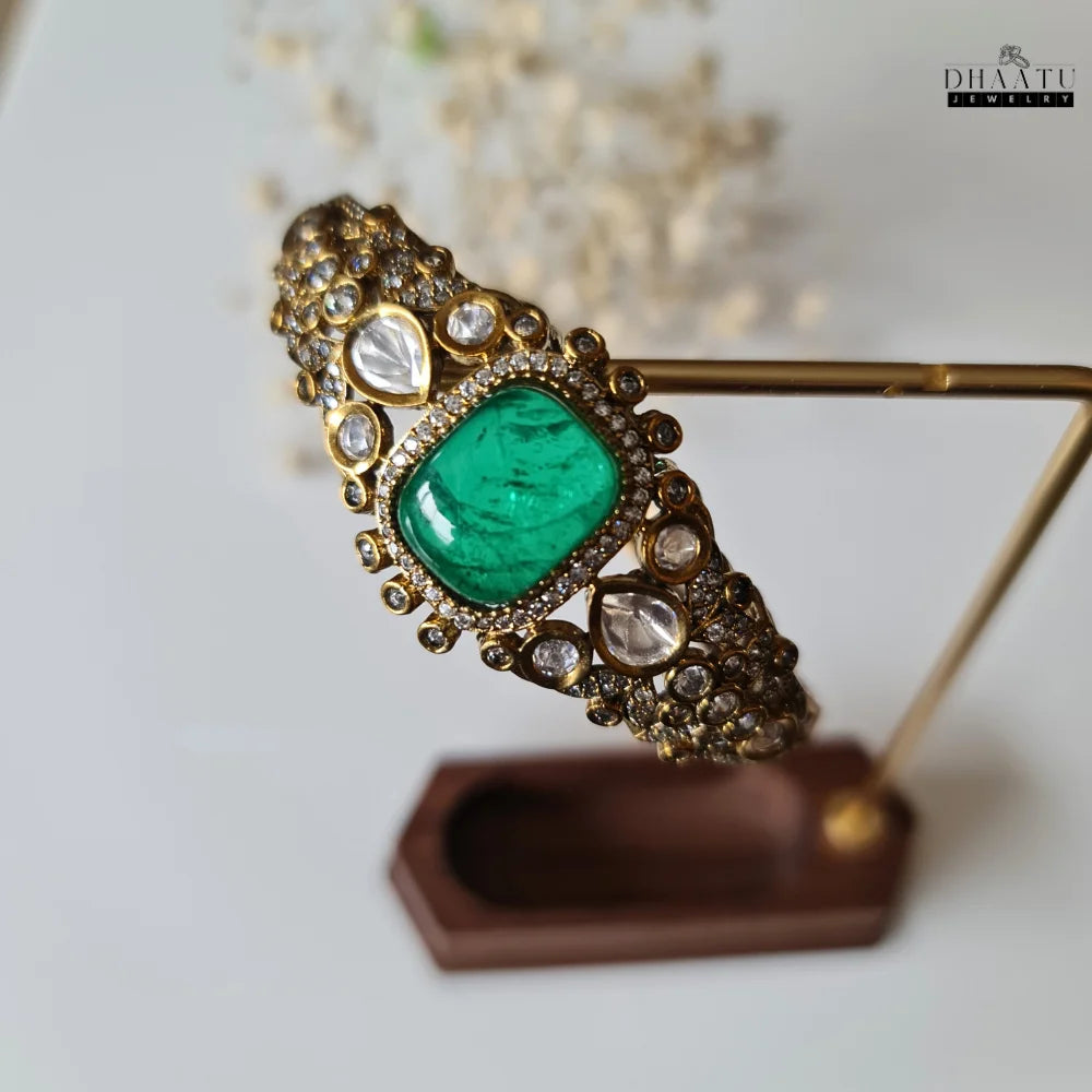 Dhaatu festive bracelet with green doublet stone and white accents displayed on a stand.
