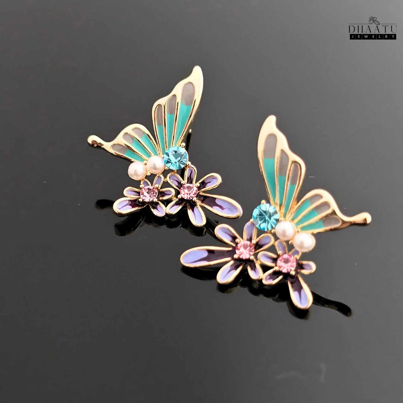 Pair of turquoise and purple butterfly and flower stud earrings with a black reflective background.