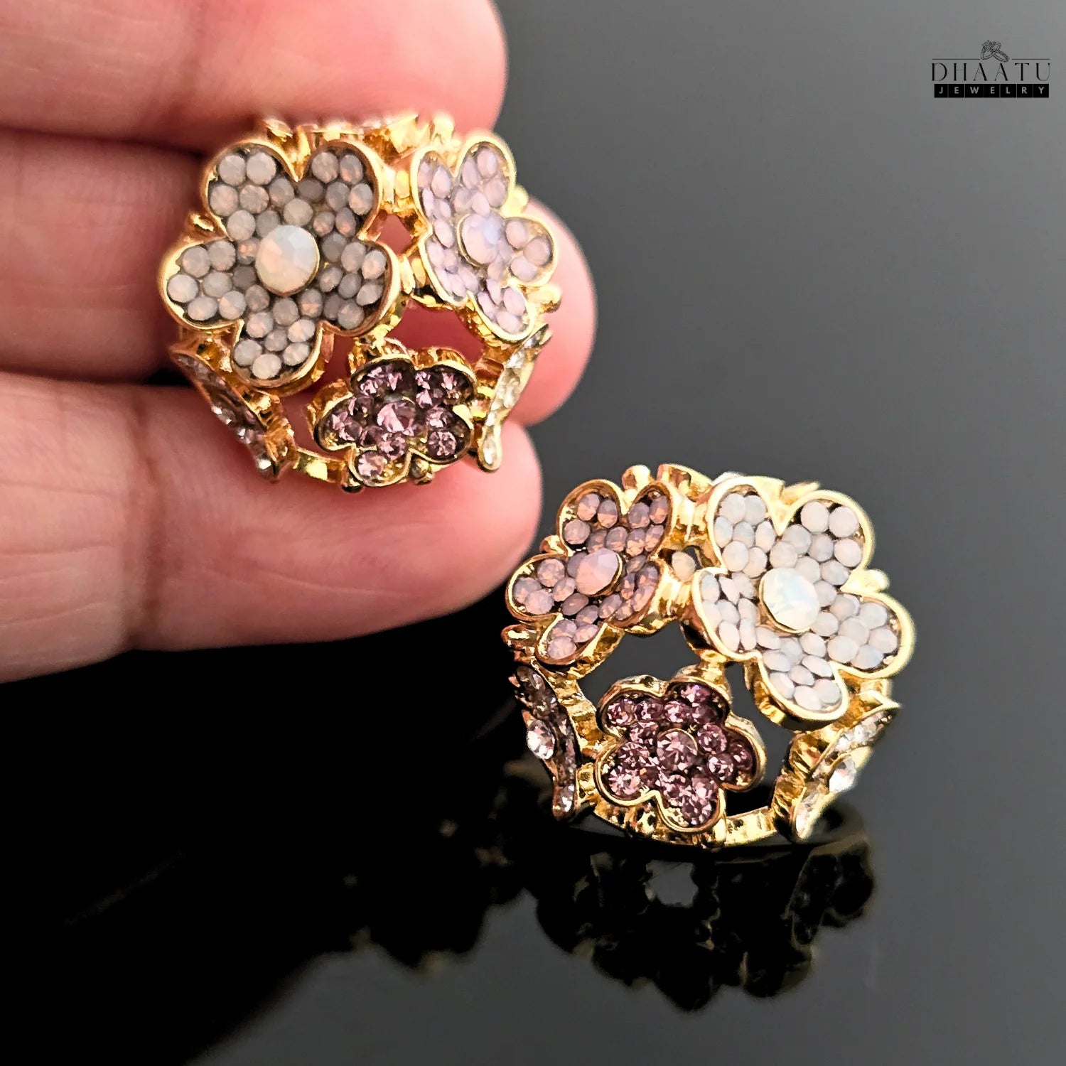 Hand holding a single rose gold-plated floral stud earring to show scale and detail.