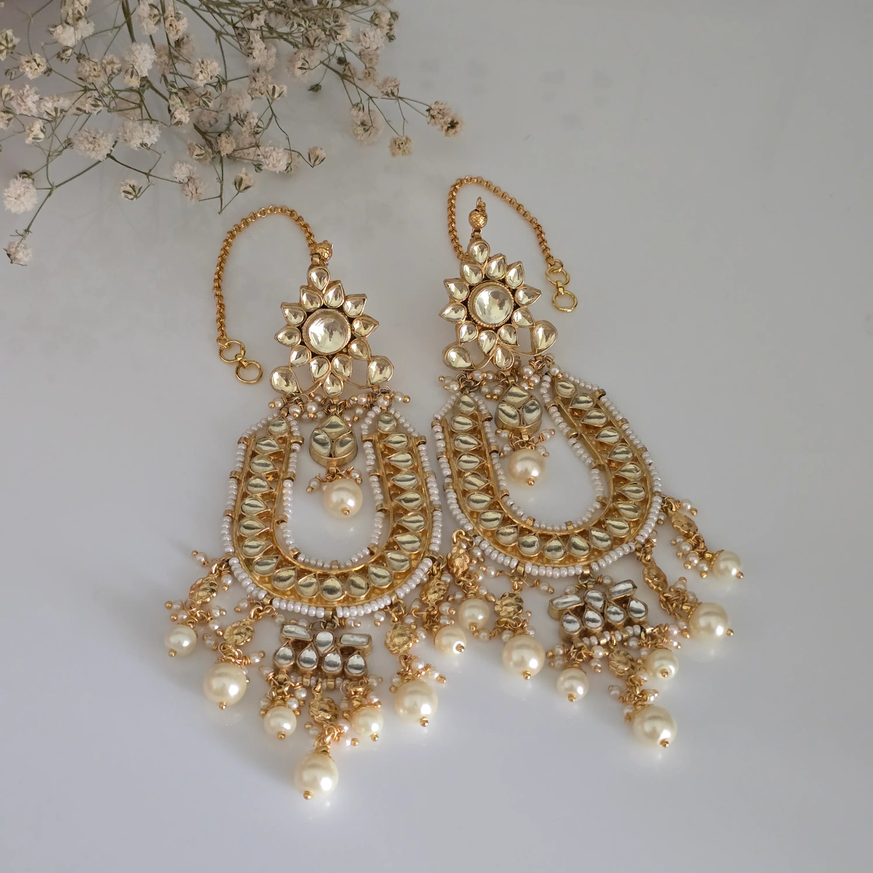 Pair of gold-plated Kundan and pearl Chandbali earrings with attached Sahare (ear chains) for traditional Indian look.