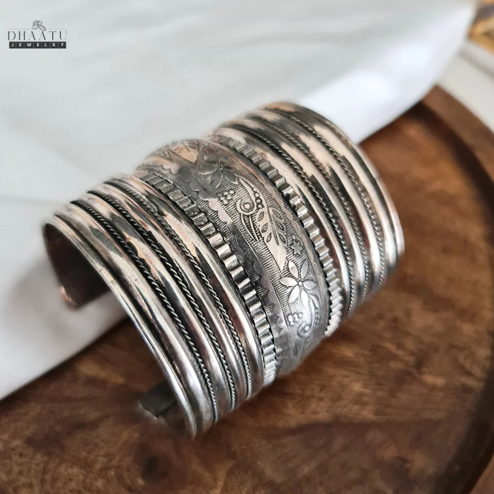 Angled view of the oxidized silver tribal cuff bracelet, highlighting its multi-layered design and silver finish on a white cloth.
