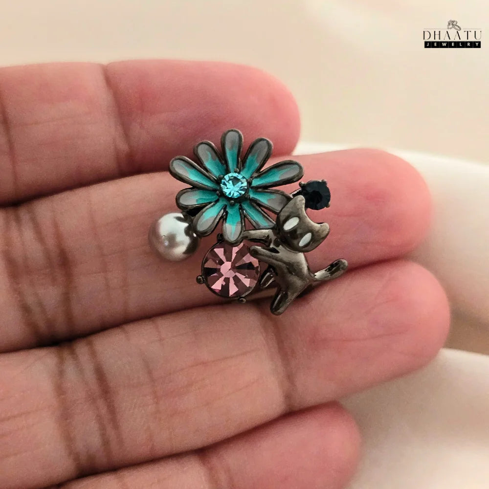 A user's hand wearing the DHAATU JEWELRY playful cat and flower ring, demonstrating its size and how it looks when worn.