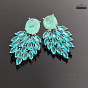 A view of the Aqua Chalcedony and marquise cut blue stone dangler earrings on a reflective dark surface, emphasizing their brilliant blue color and design.
