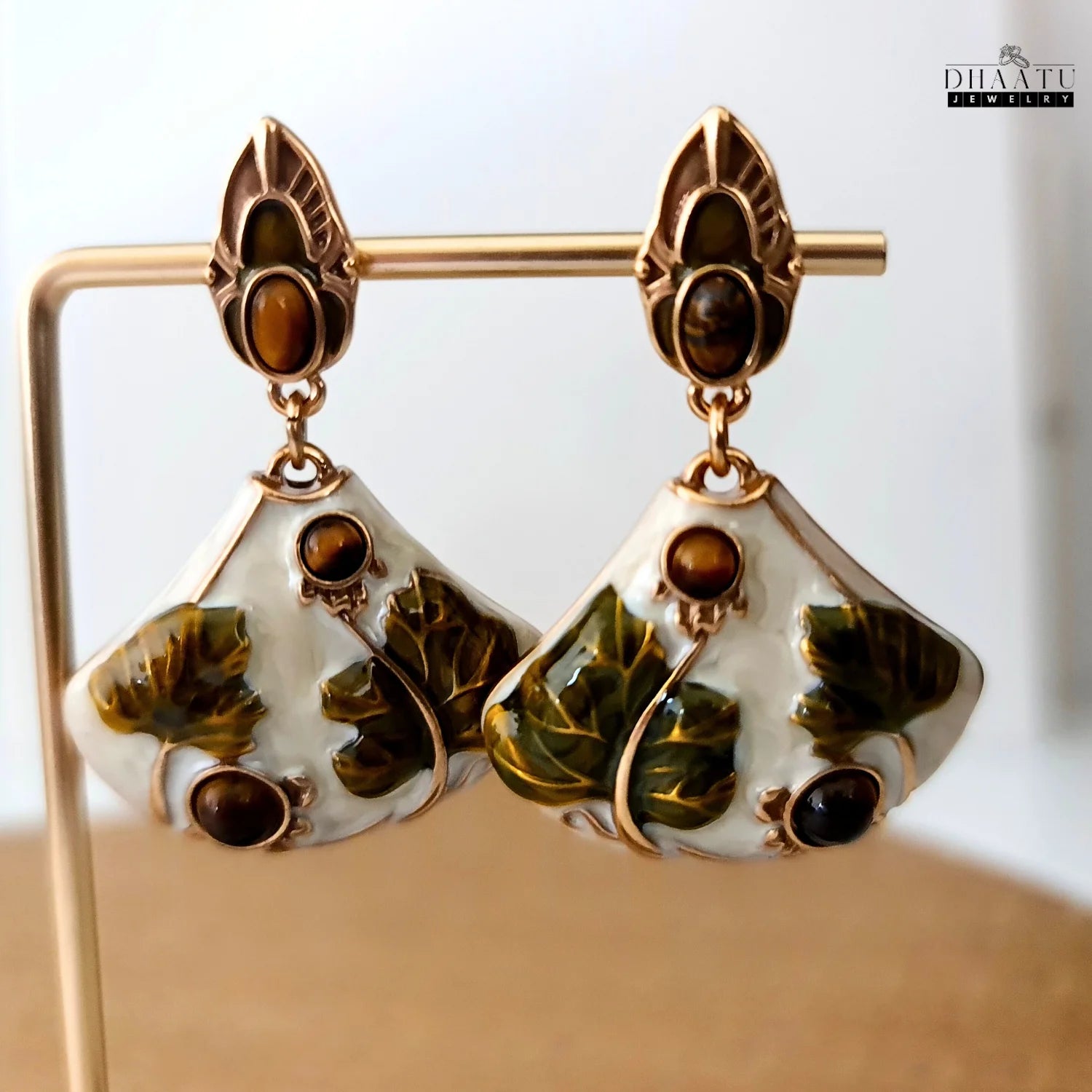 Close-up of Art Nouveau lotus earrings hanging on a rose gold display stand, highlighting the detail and craftsmanship.
