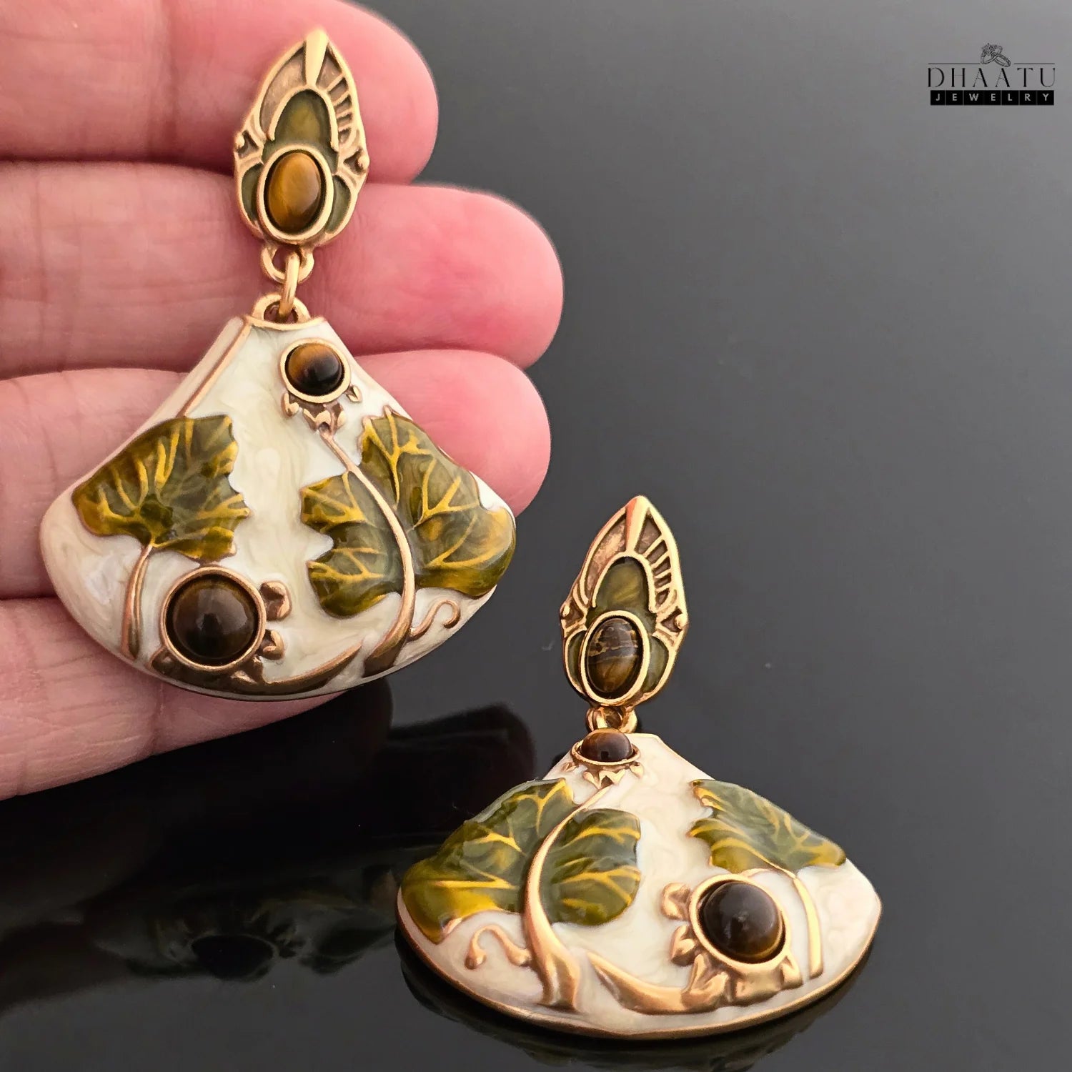 Art Nouveau lotus drop earrings held in a hand for scale, showing the size and design from a different angle.