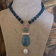 Elegant blue apatite round beaded necklace with multi-color pink, green, and blue natural stone pendant, semi-precious gemstone jewelry on a display