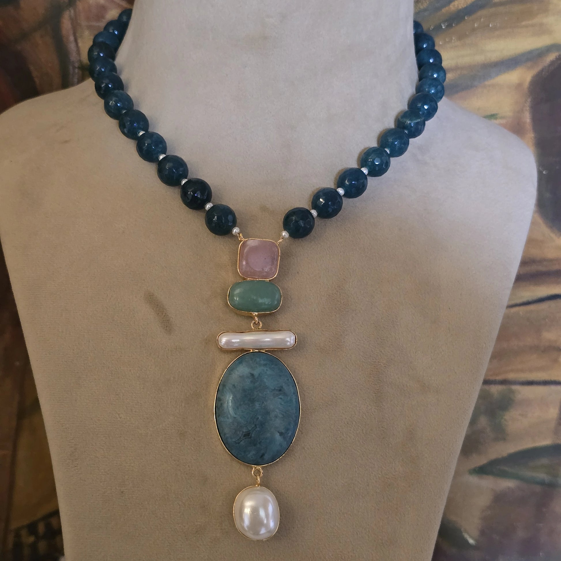 Elegant blue apatite round beaded necklace with multi-color pink, green, and blue natural stone pendant, semi-precious gemstone jewelry on a display