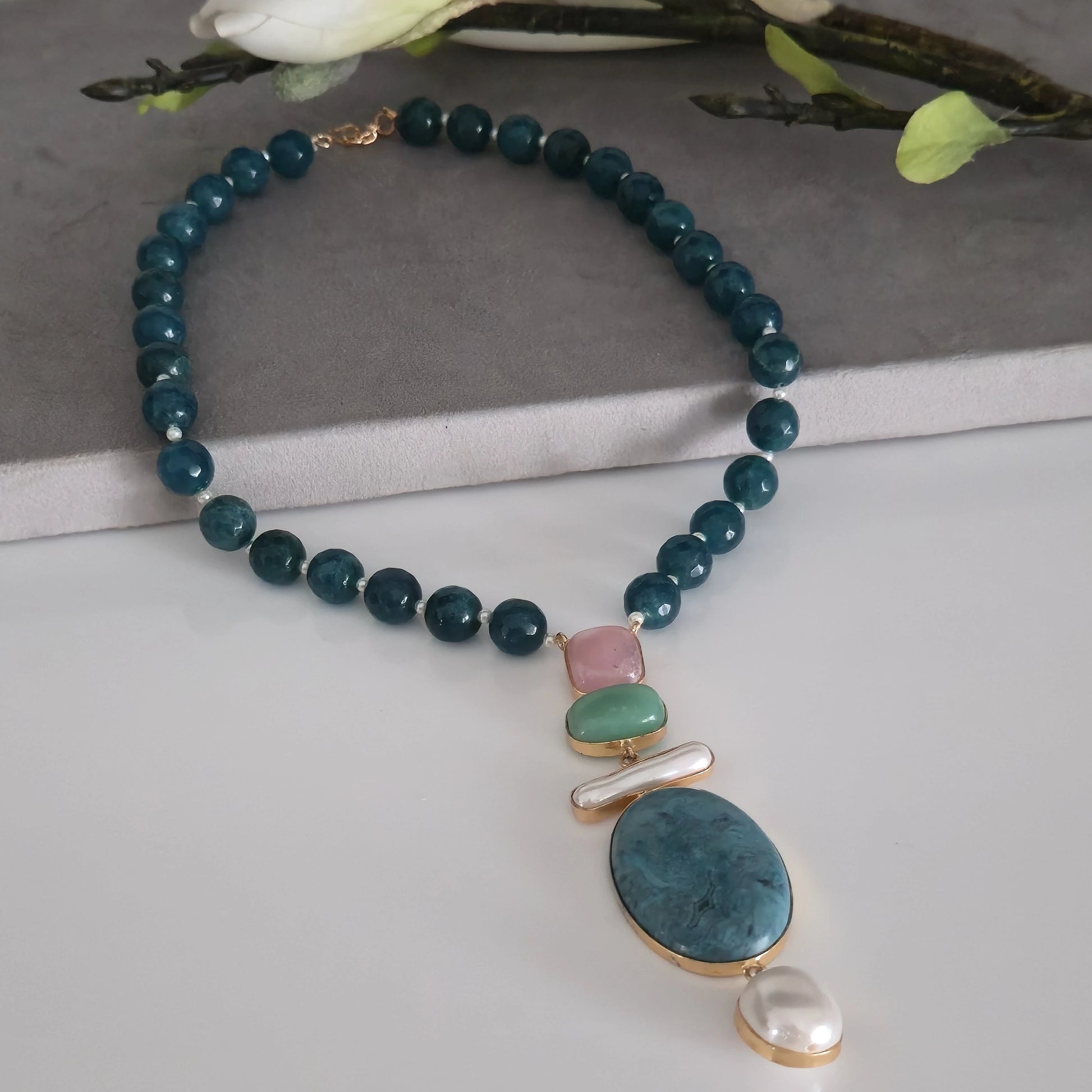 Elegant blue apatite round beaded necklace with multi-color pink, green, and blue natural stone pendant, semi-precious gemstone jewelry on a white background