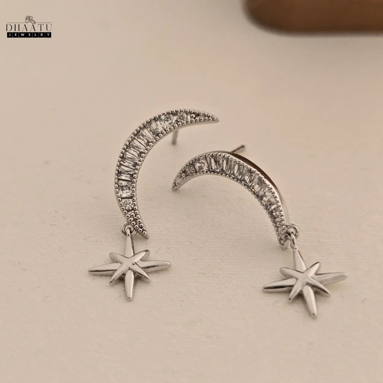 Front view of celestial moon and star dangle earrings with clear zircon stones, showcasing the unique design