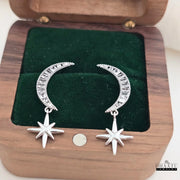 Celestial moon and star dangle earrings displayed in an open wooden jewelry box, showcasing their elegant design