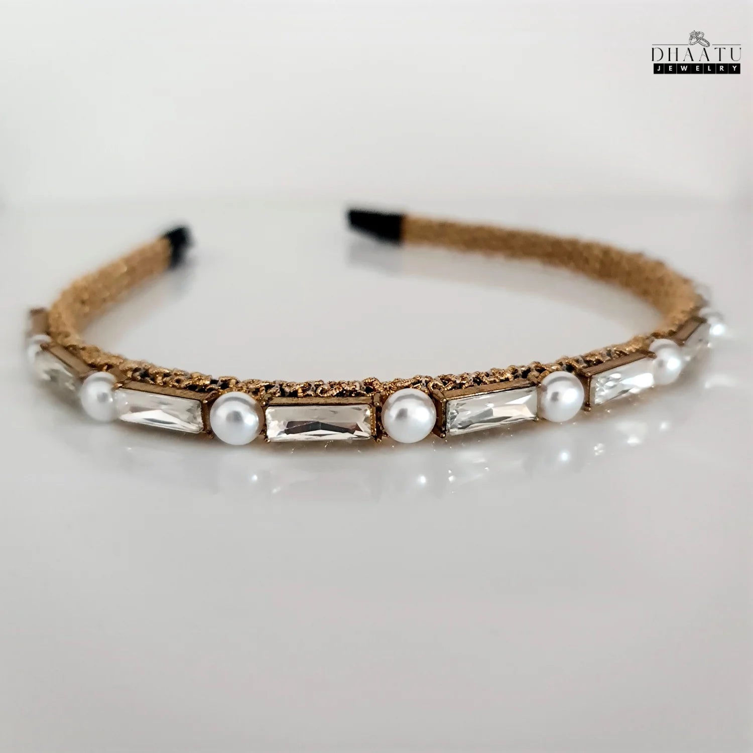 Chic artificial jewelry hairband with gold weave, pearls, and clear crystals on a white background, highlighting its contemporary design.