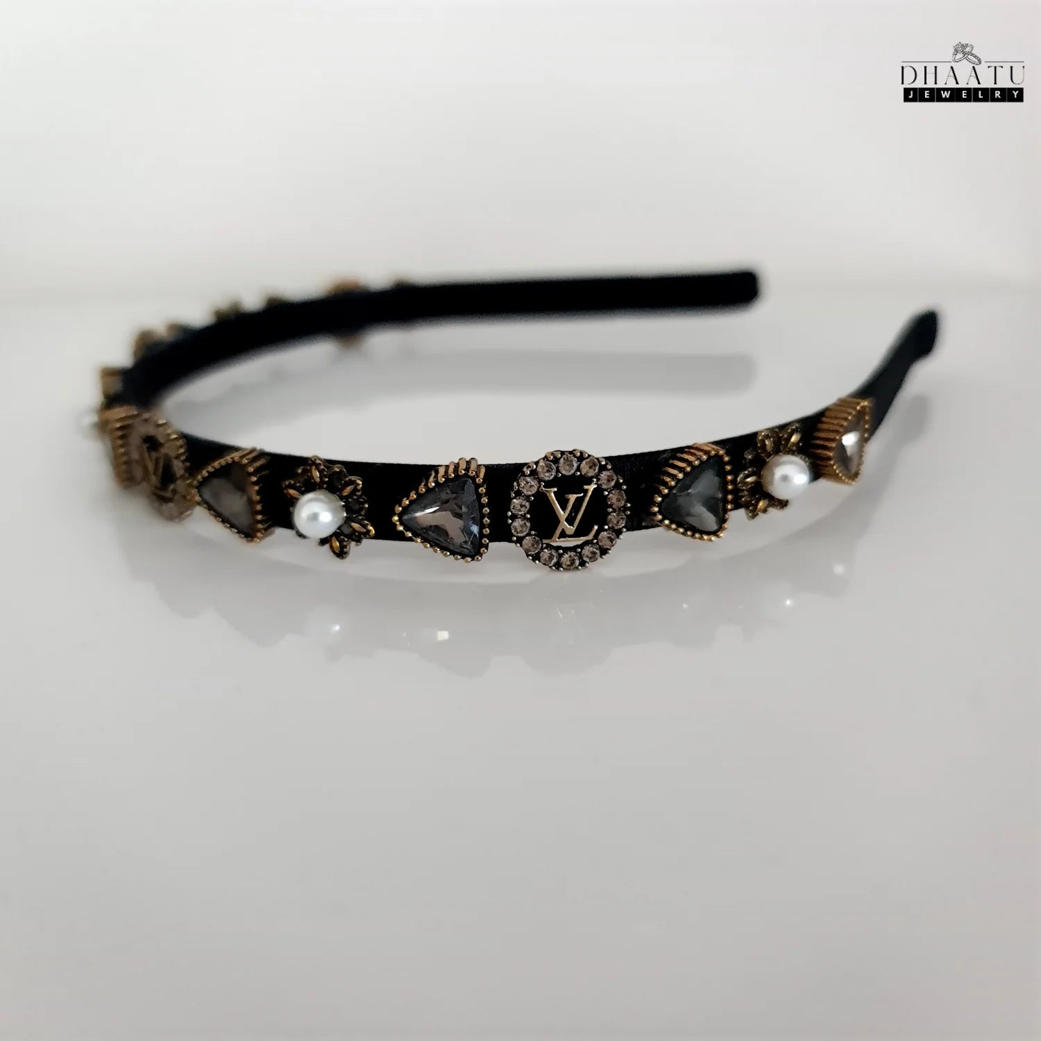 Full view of a chic black hairband with sparkling crystal designs and faux pearls on a white background