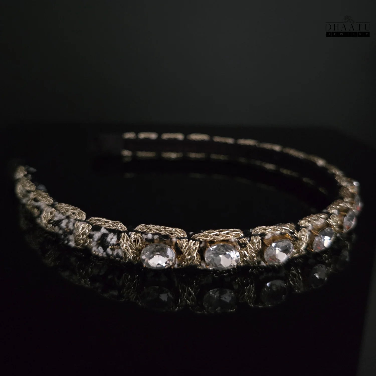 Detailed view of a Western headband with clear crystals and intricate golden woven texture on a black background.

