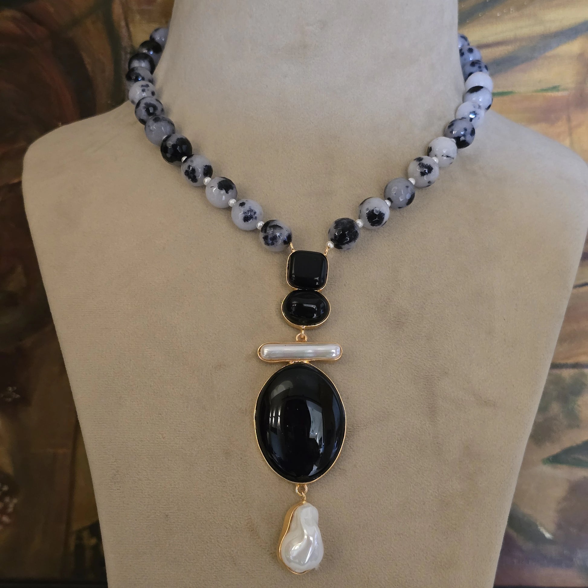 Handcrafted black and white dalmatian jasper beaded necklace with unique black stone and pearl drop pendant, natural stone statement jewelry for women on a display