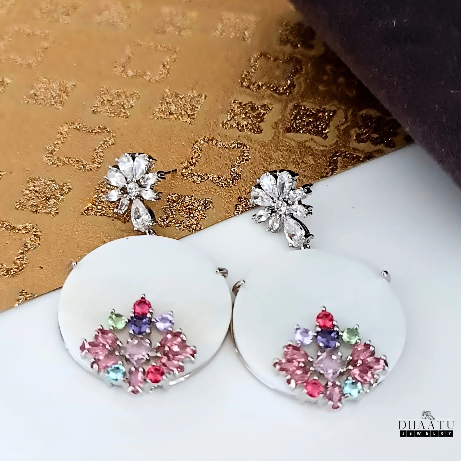 Dhaatu Jewelry floral stud dangle earrings with colorful stones and sparkling cubic zirconia on a decorative background.