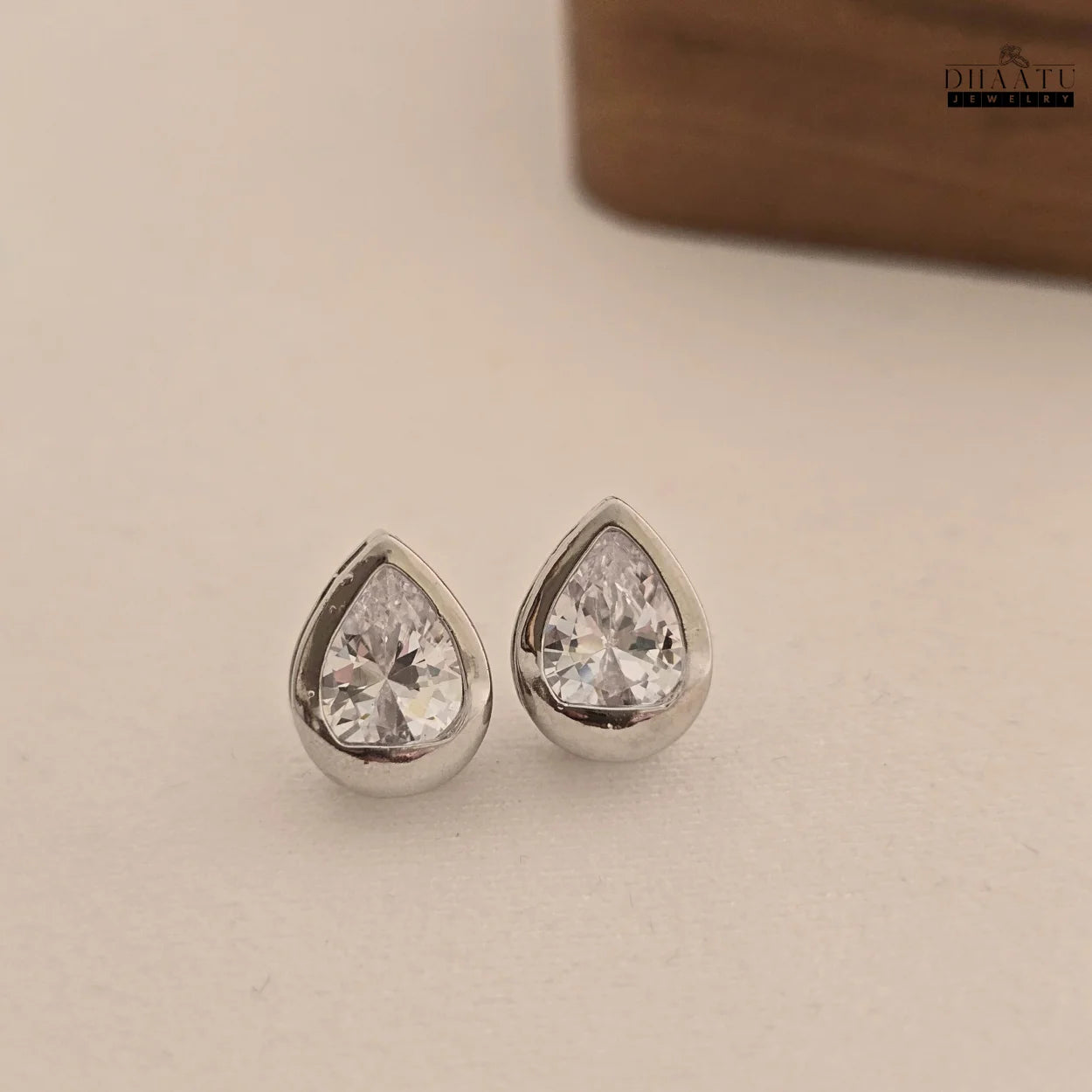 DHAATU JEWELRY pear-cut American diamond stud earrings presented neatly on a clean white background.

