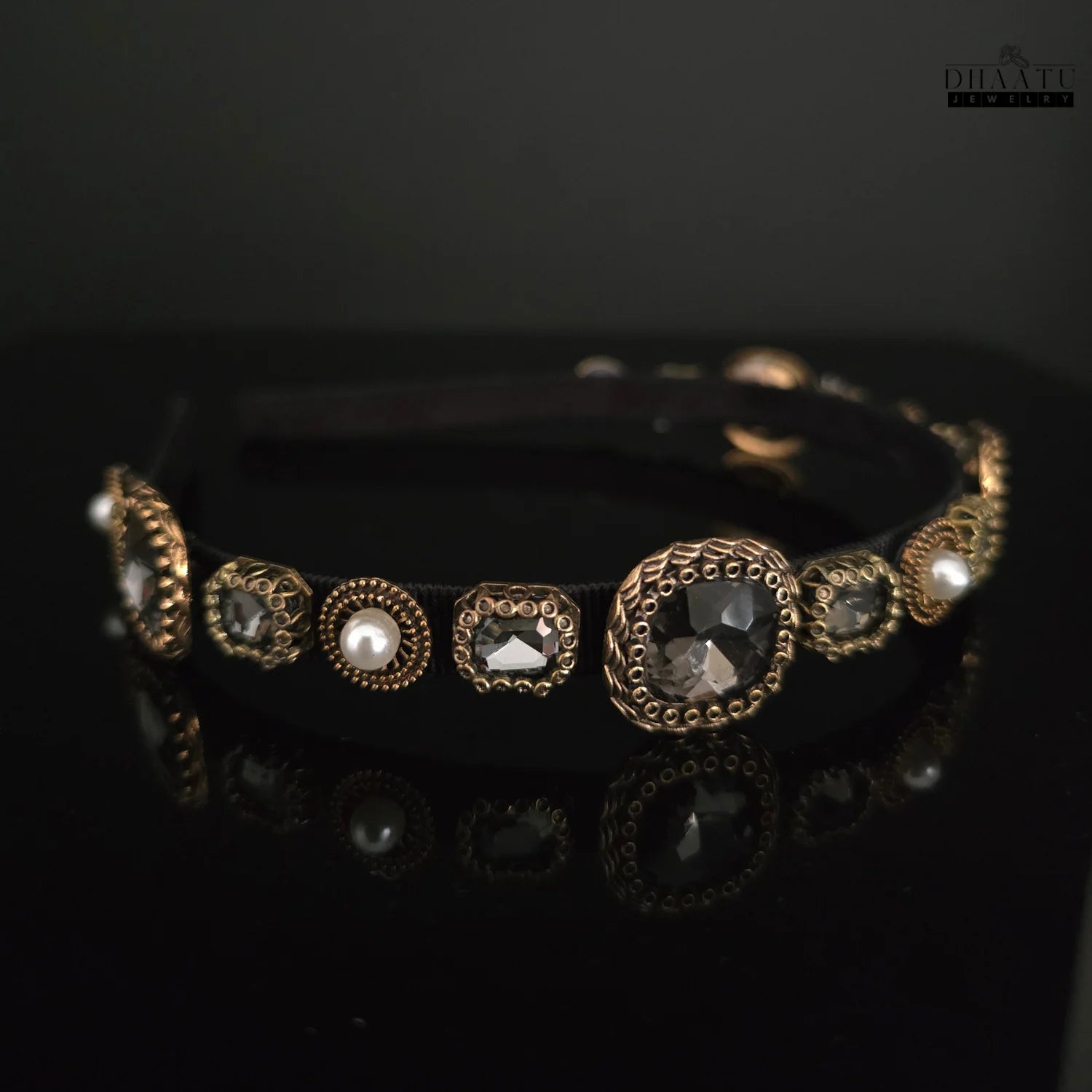 Close-up view of Dhaatu Jewelry black and gold hairband with intricate crystal and pearl details.