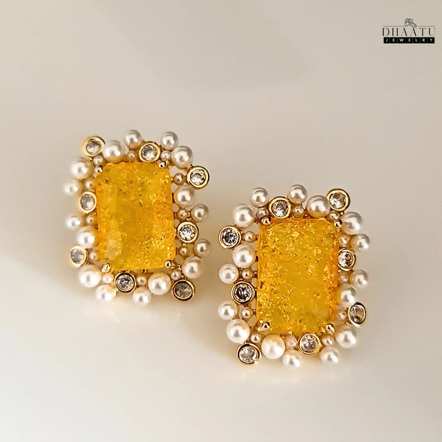 Front view of DHAATU JEWELRY earrings with a central citrine stone surrounded by polki and pearls, presented on a clean white background.