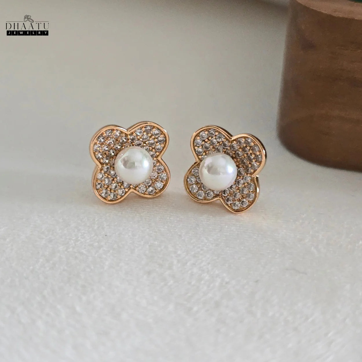 Pair of DHAATU JEWELRY gold-plated clover pearl and zircon stud earrings on a white background, clearly showing the design and finish.