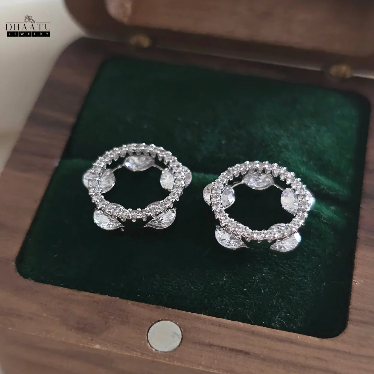 Close-up of Dhaatu Jewelry sparkling circle stud earrings in a wooden box, showcasing the pave and cluster CZ design
