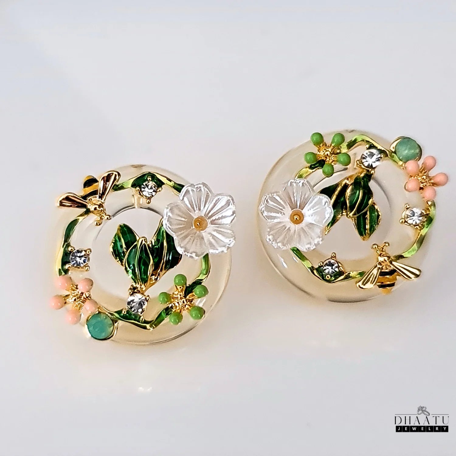 A pair of nature-inspired DHAATU JEWELRY bee and floral earrings against a clean white background, ideal for product listings.