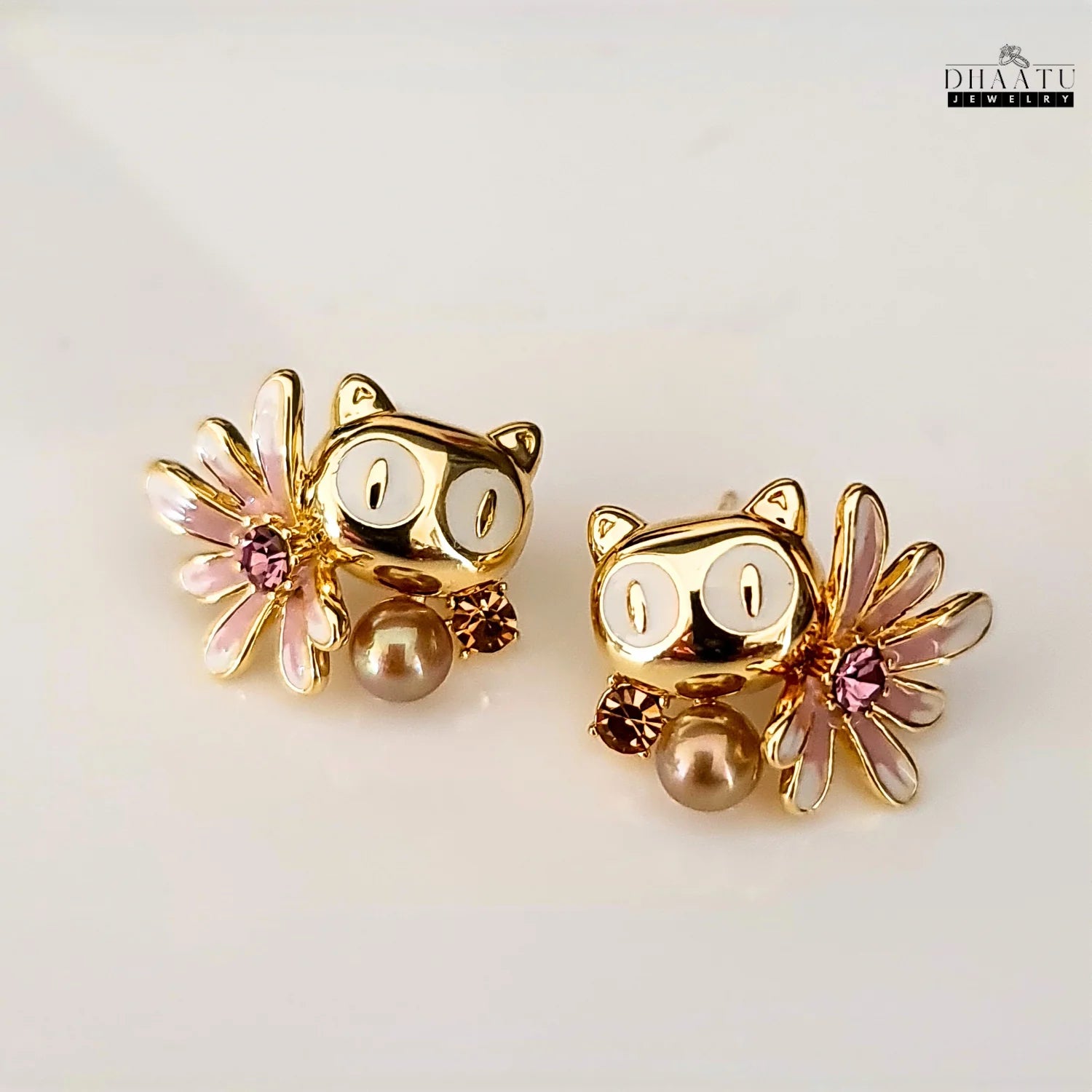 Dhaatu Jewelry gold-toned owl stud earrings with white eyes, pink flower, and mocha-colored pearl-like drop.