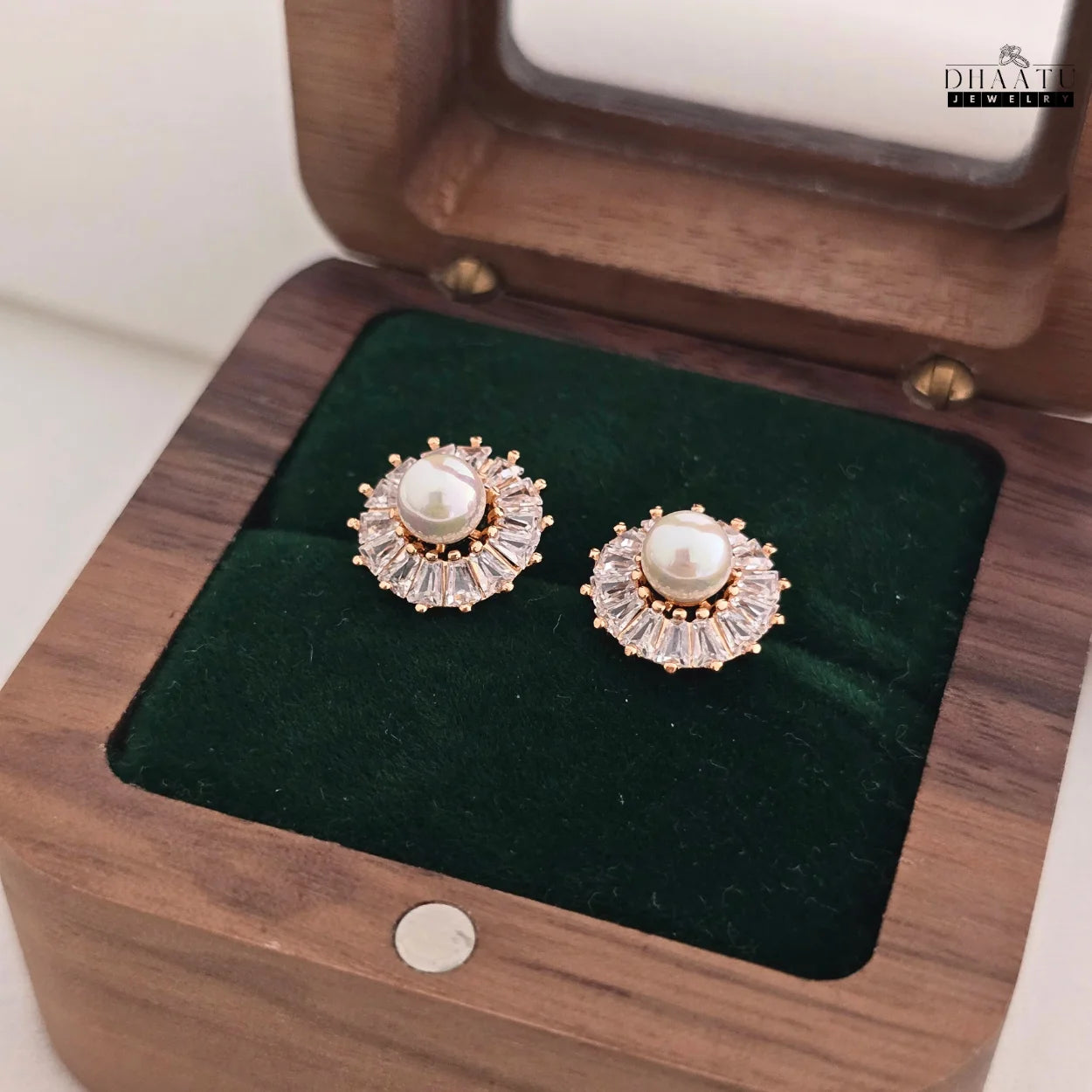 DHAATU JEWELRY Pearl and Cubic Zirconia Sunburst Stud Earrings displayed in a dark wooden jewelry box with green velvet lining