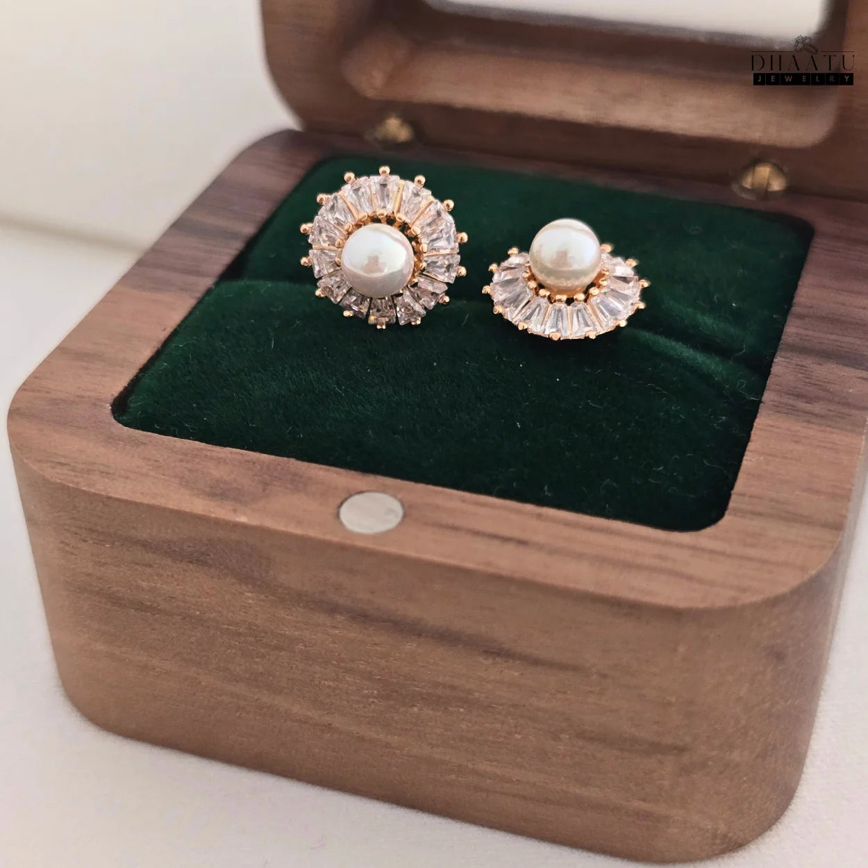 Angled view of DHAATU JEWELRY Pearl and Cubic Zirconia Sunburst Stud Earrings inside a wooden jewelry box.


