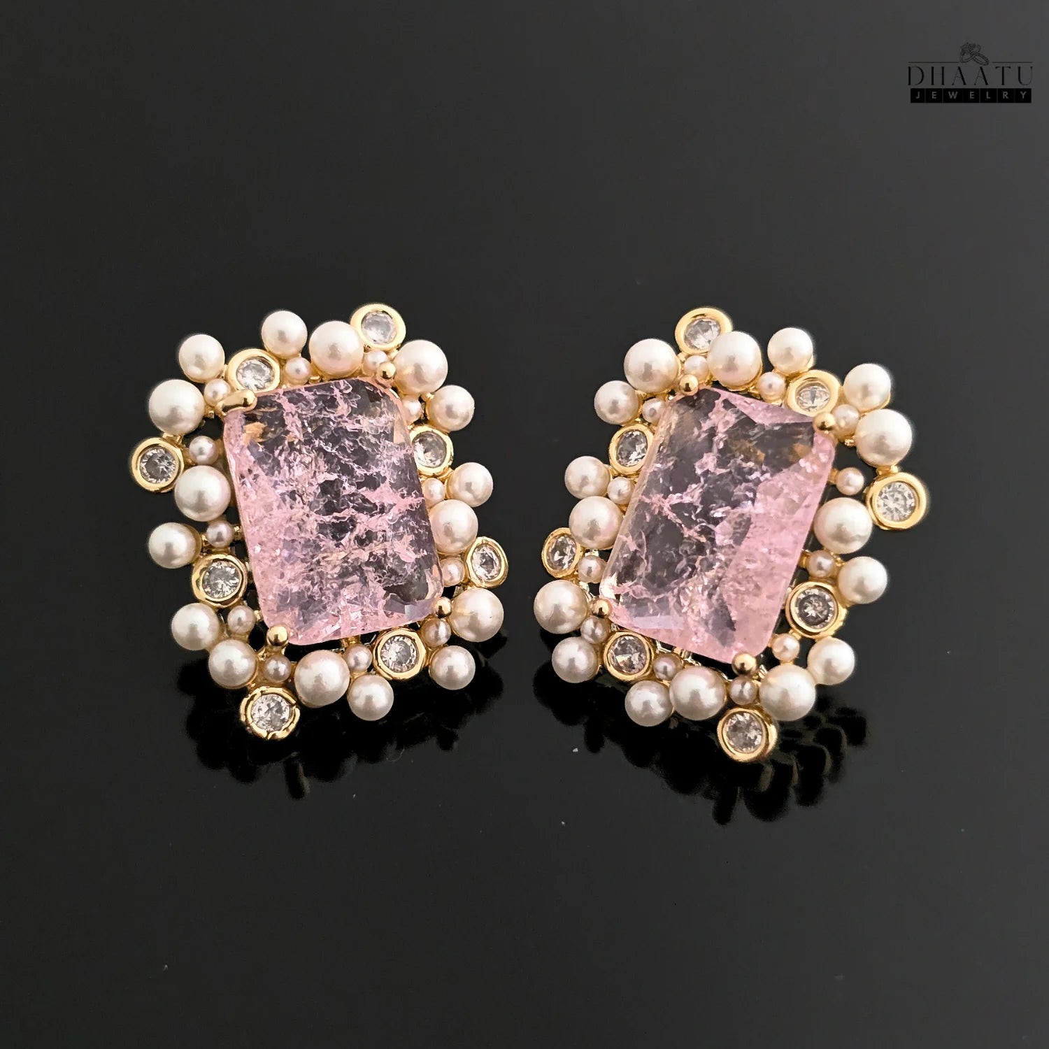 Pair of earrings with pink stones and pearl-like beads on a black background