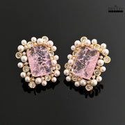 Pair of earrings with pink stones and pearl-like beads on a black background