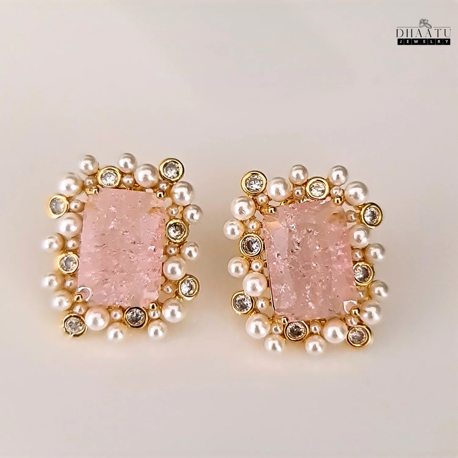 Pair of earrings with pink gemstones and pearl-like beads on a light background