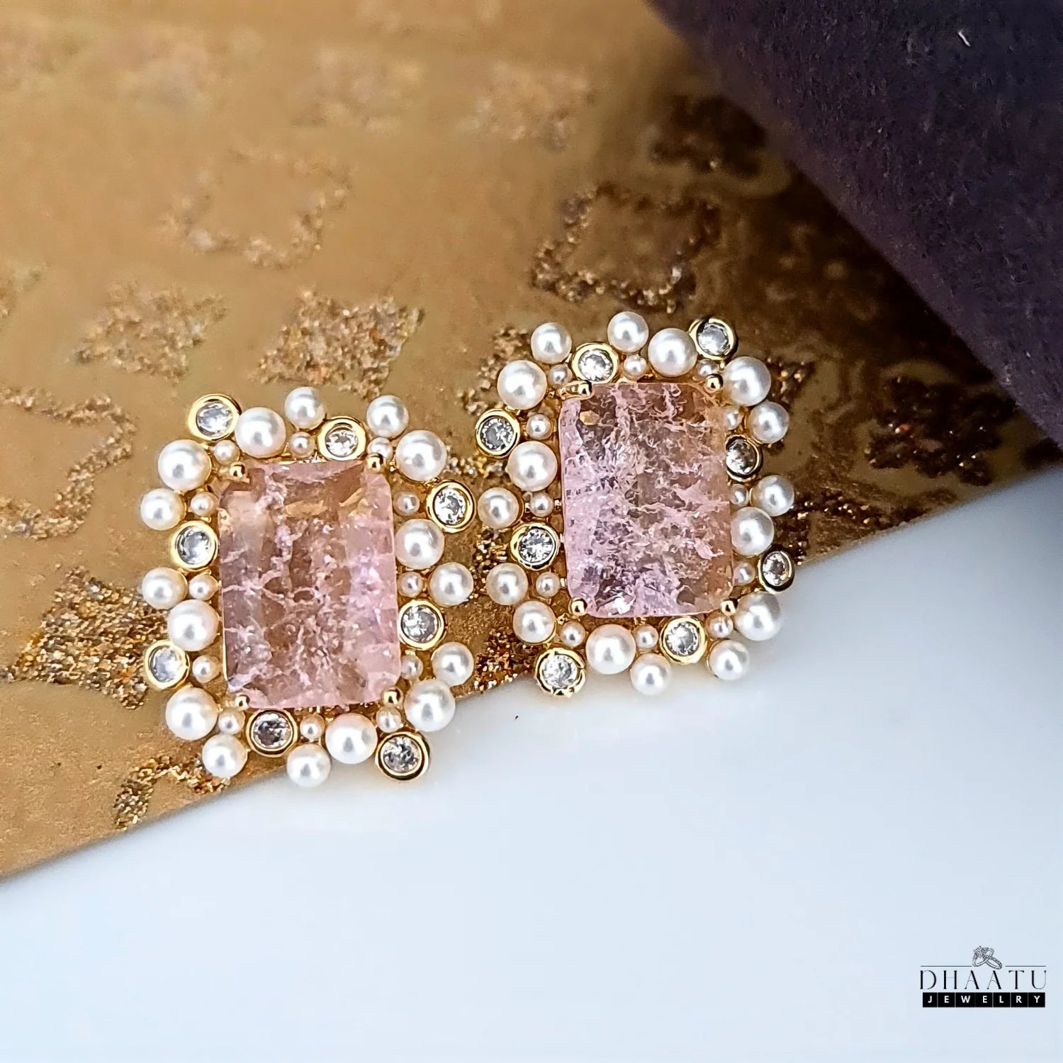 Earrings with pink gemstones and pearls on a textured surface