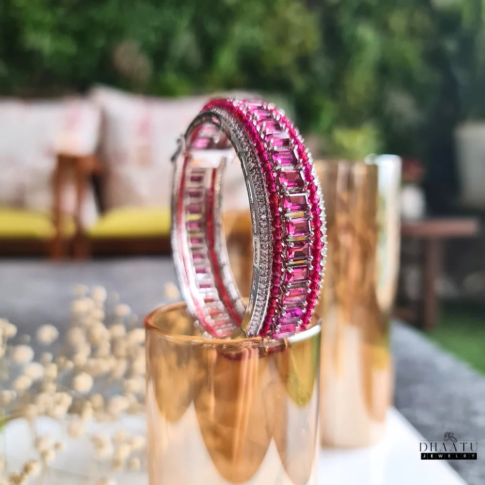Dhaatu Jewelry pink ruby and diamond simulant bangle bracelet displayed elegantly in an outdoor setting.

