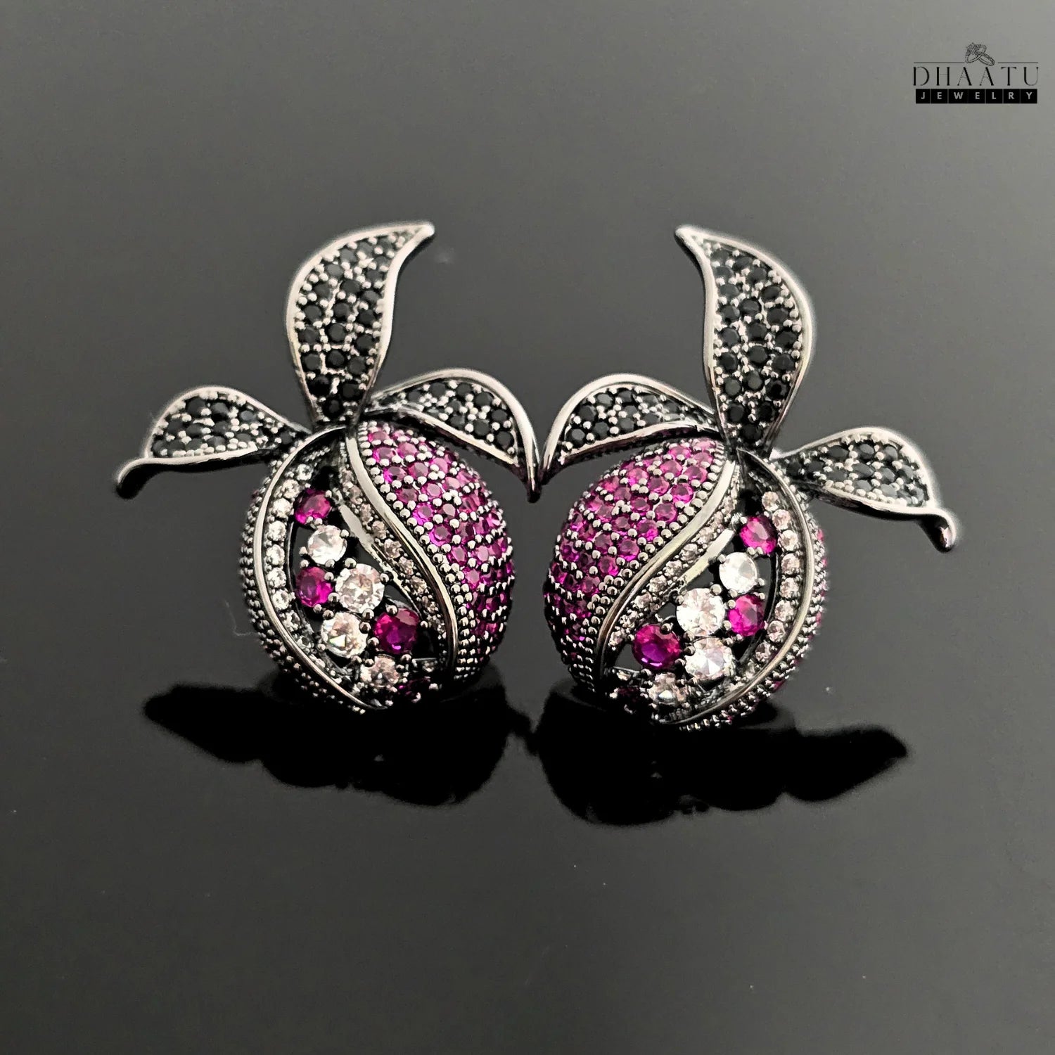 Pomegranate-inspired stud earrings with black rhodium finish, featuring pink, white, and black zircon stones on a black reflective background.