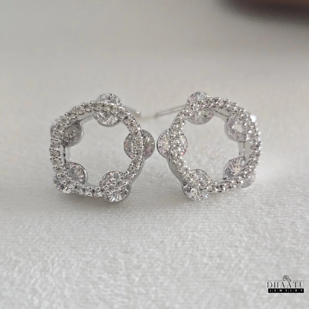 Front view of Dhaatu Jewelry round cubic zirconia stud earrings on a white background, highlighting the intricate details