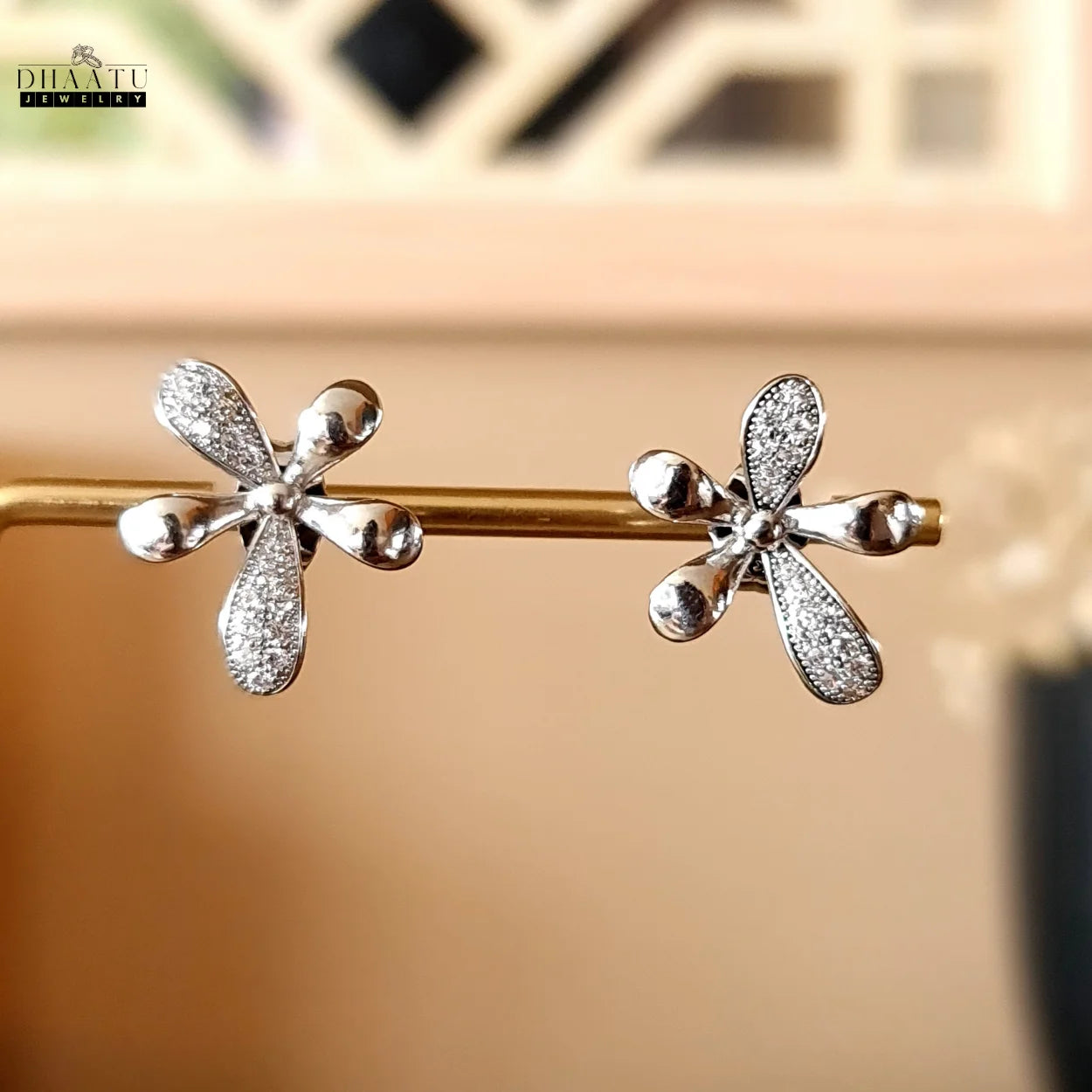 Dhaatu Jewelry silver-plated floral stud earrings displayed on a gold jewelry stand