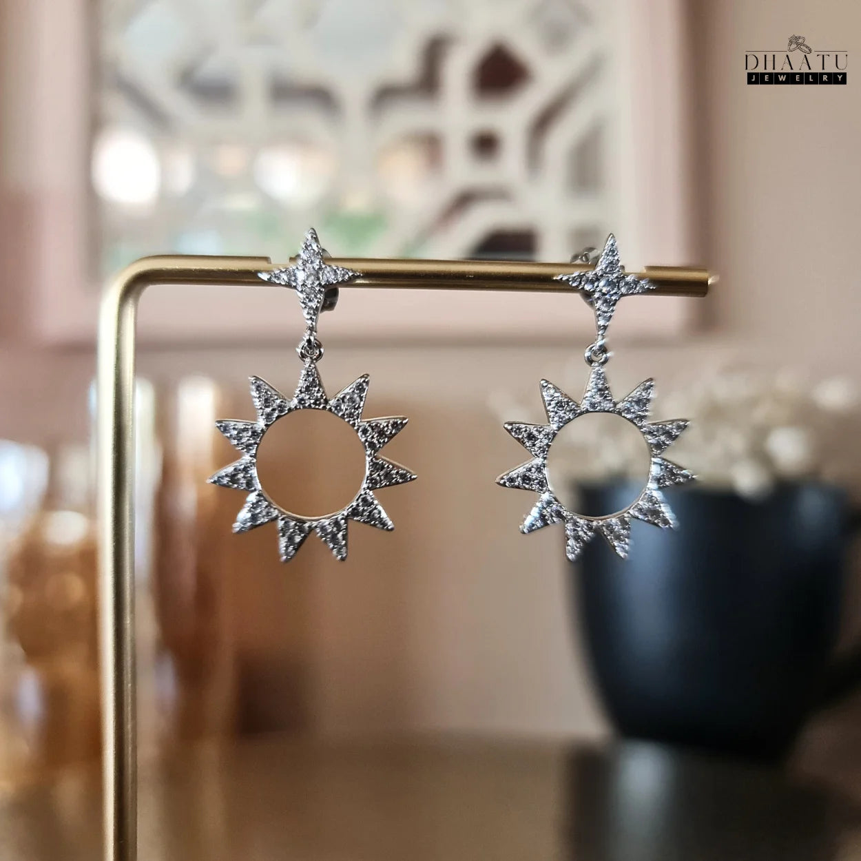 Close-up display of Dhaatu Jewelry silver-plated star and sunburst dangle earrings with zircon stones, showcasing intricate details and sparkle.