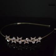 Front view of DHAATU JEWELRY Starlight Crystal Embellished Gold-Toned Hairband with five sparkling star designs and clear round crystals