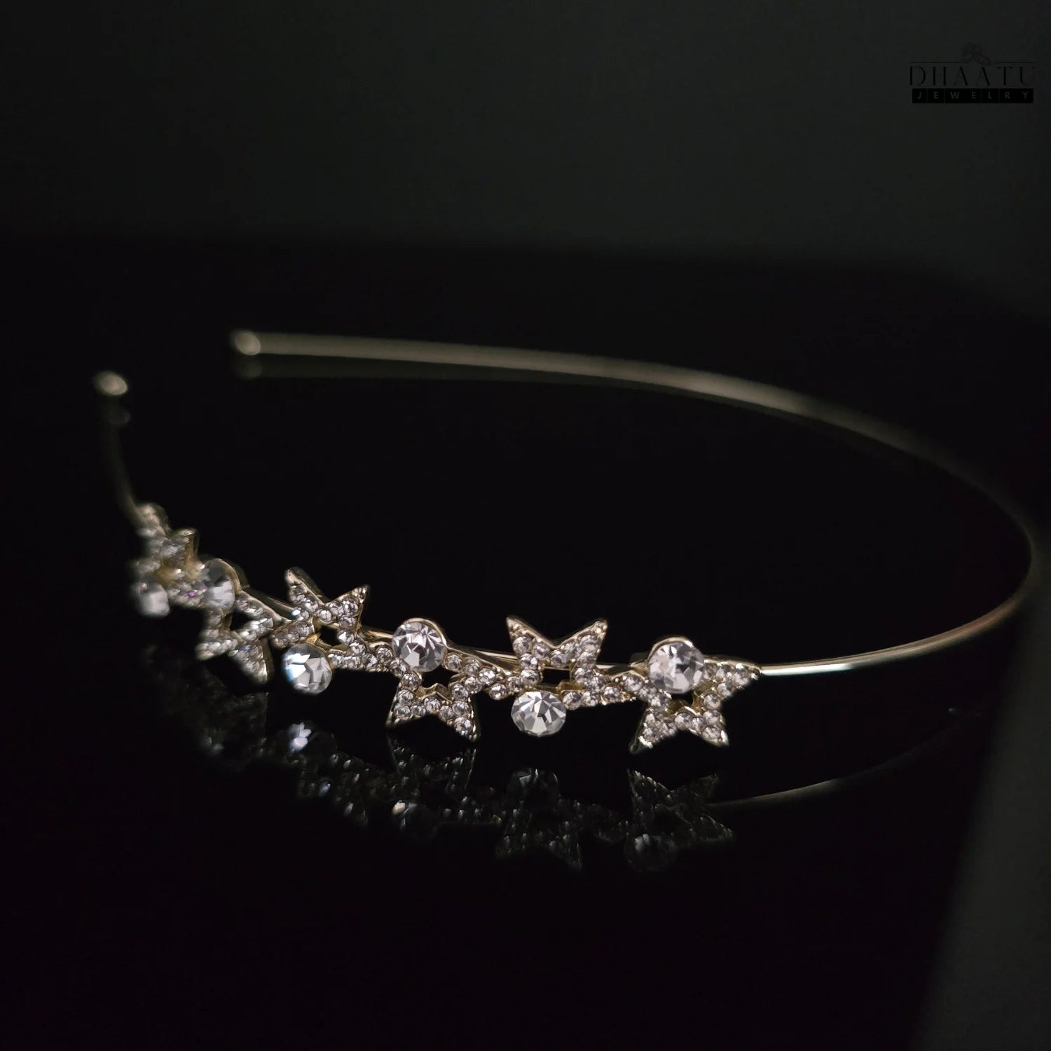 Side angle of DHAATU JEWELRY Starlight Crystal Embellished Gold-Toned Hairband, showcasing the intricate crystal details on a dark background