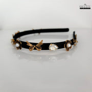 Side view of Dhaatu Jewelry Western-style black hairband with gold bows and flower embellishments against a white background