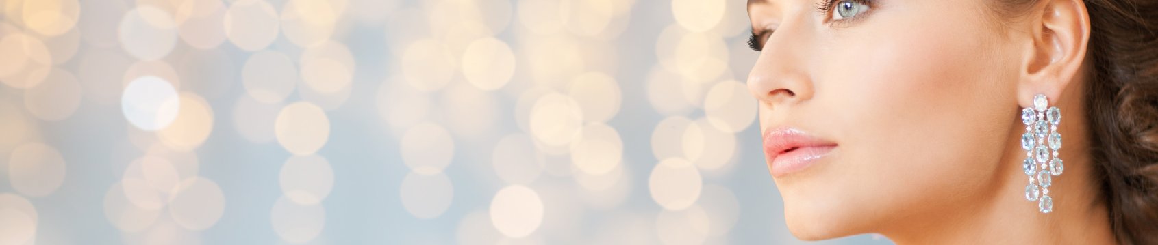 Close-up of a woman wearing silver earrings with a blurred bokeh background