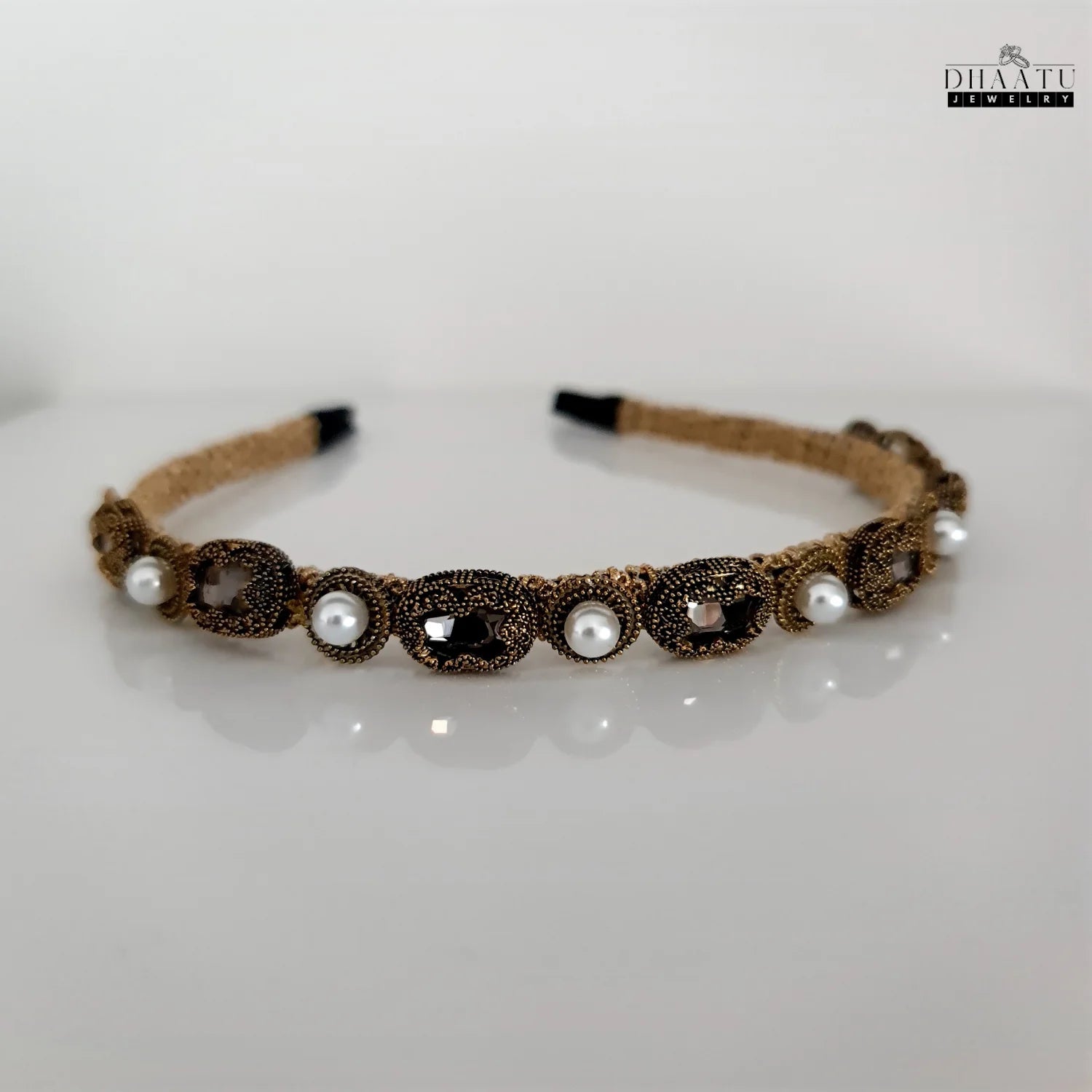 Elegant gold-toned hairband with pearls and crystals on a white background, showcasing intricate details