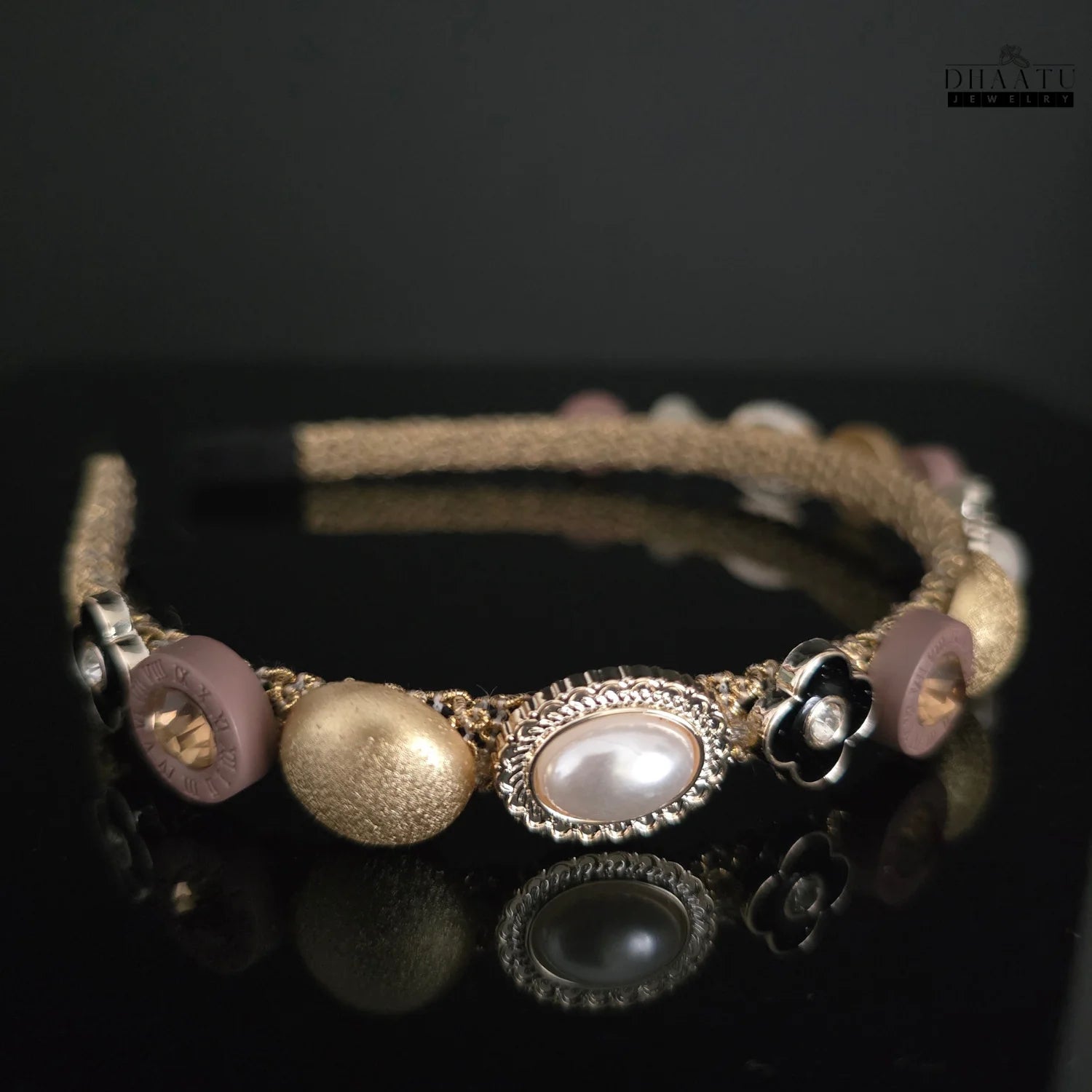 Elegant gold and pearl beaded headband featuring textured gold beads, faux pearls in ornate settings, and black flower accents on a dark background