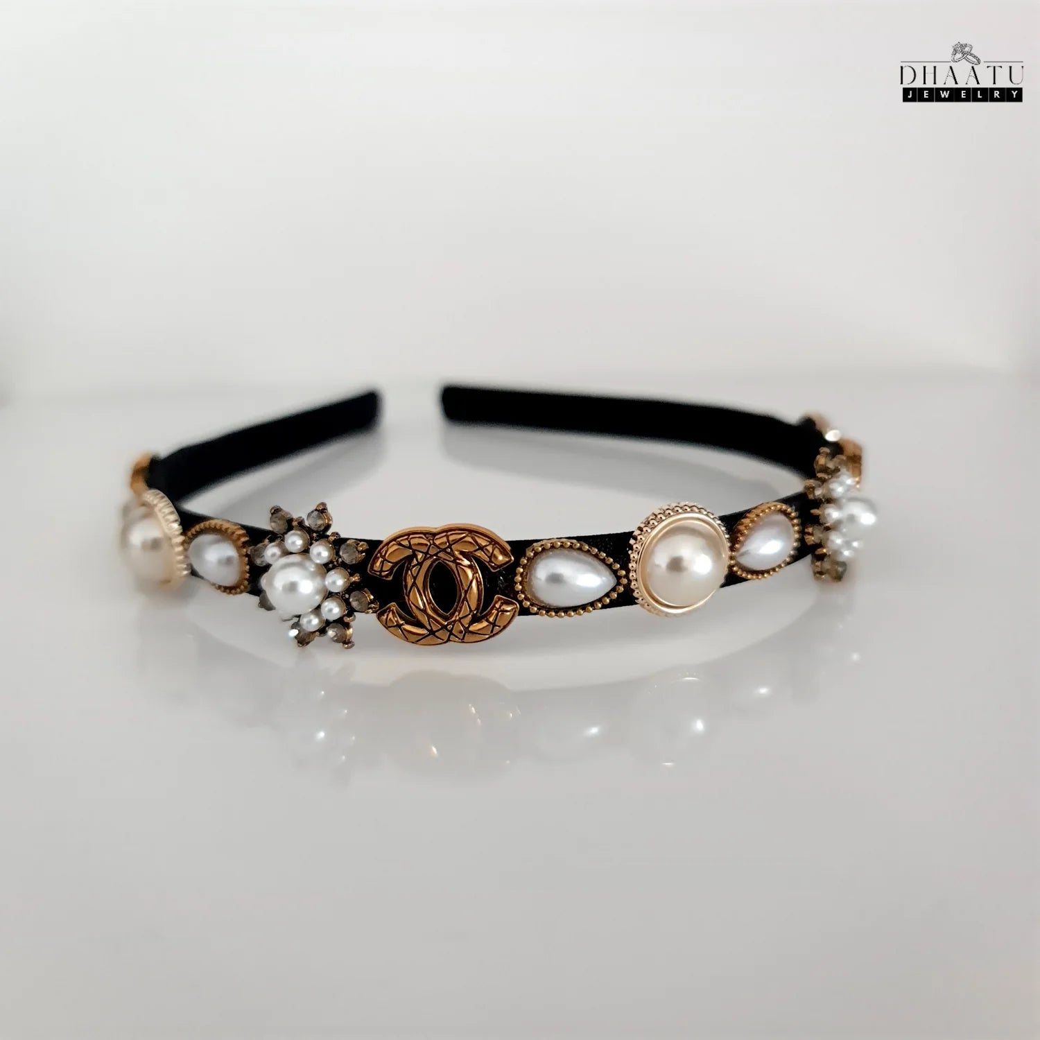 Full view of an elegant black hairband with faux pearls and gold details on a white background, suitable for modern western attire.