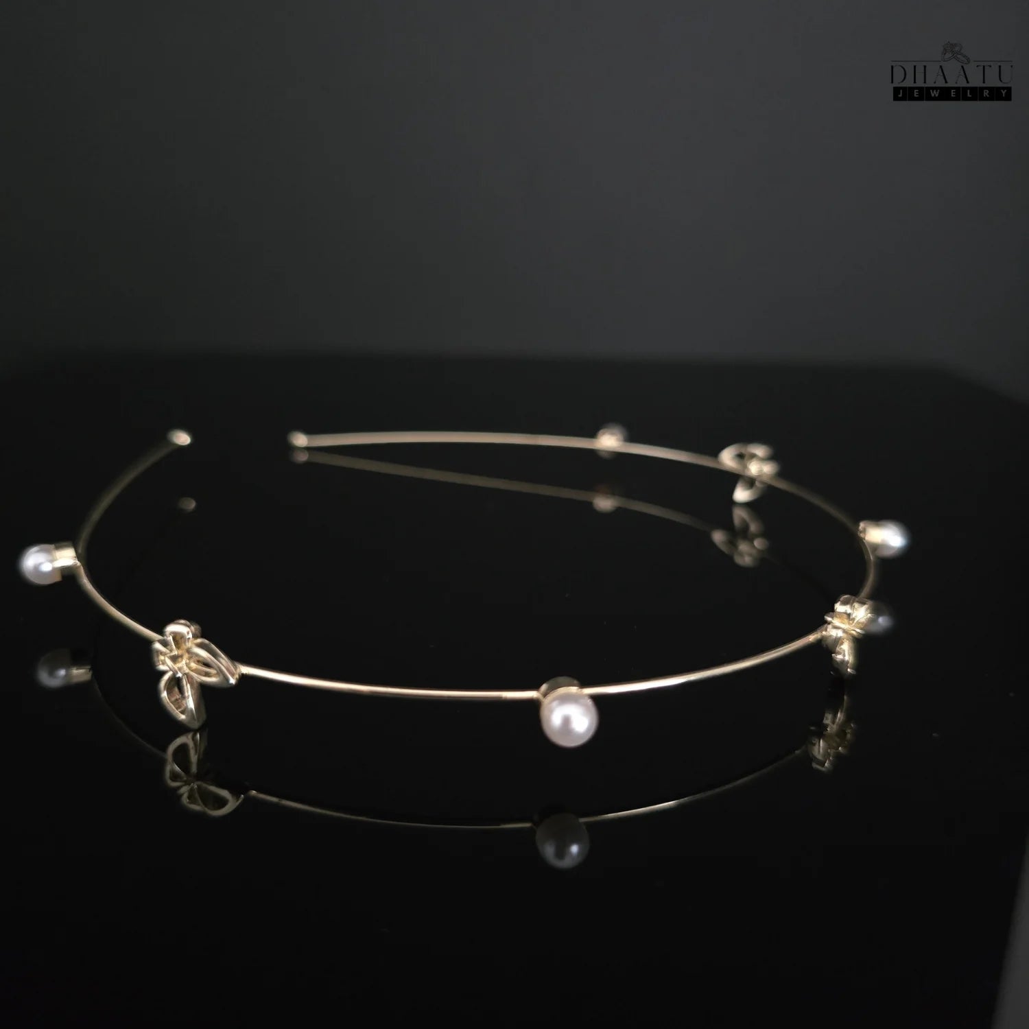 Angled view of the Dhaatu Jewelry golden butterfly and pearl modern hairband, showing multiple butterfly and pearl details on a dark background