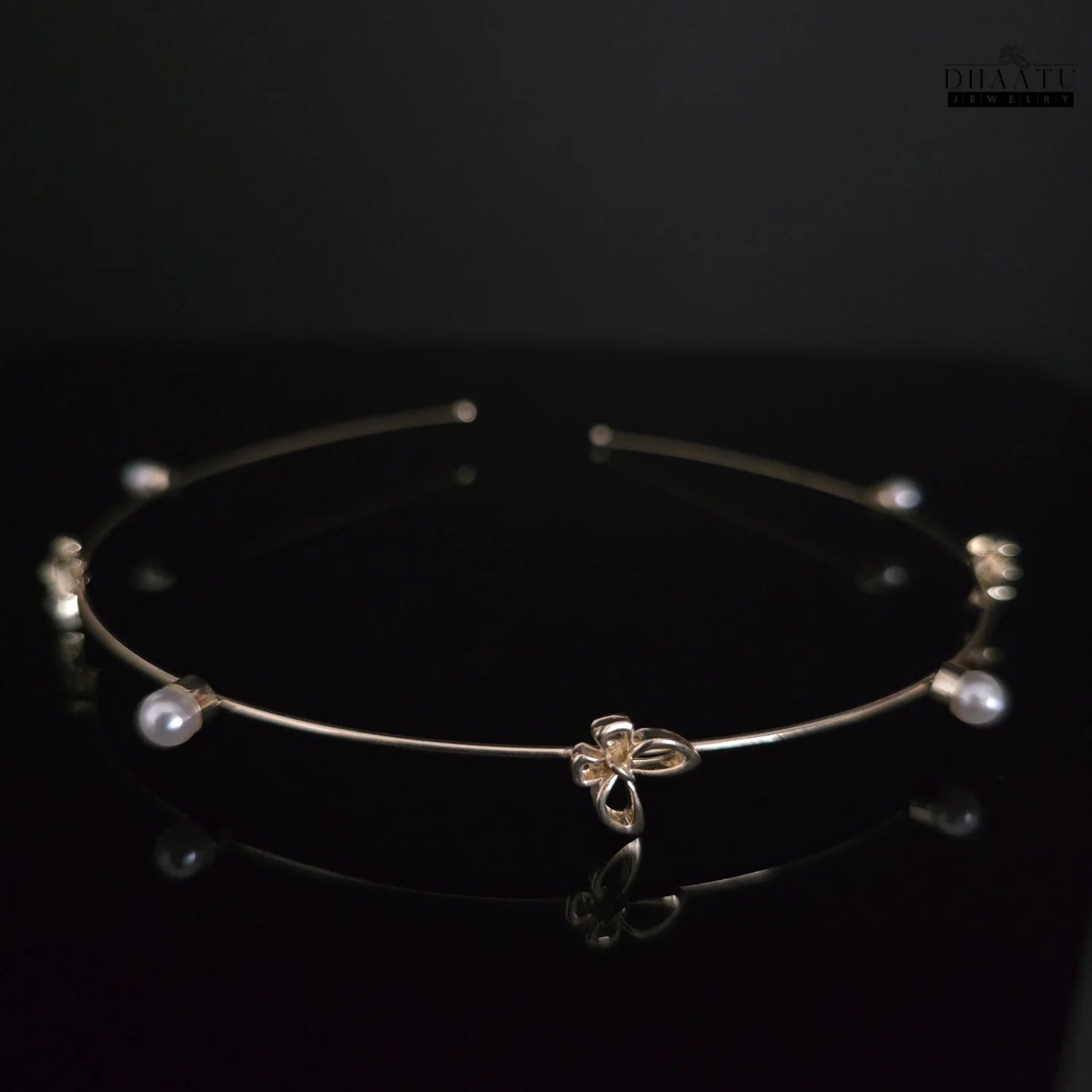 Golden butterfly and pearl hairband on a dark reflective surface, highlighting the subtle shimmer of the golden butterflies and pearls