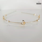 Front view of golden butterfly and pearl embellished modern hairband by Dhaatu Jewelry, showcasing intricate details and lustrous pearls on a white background