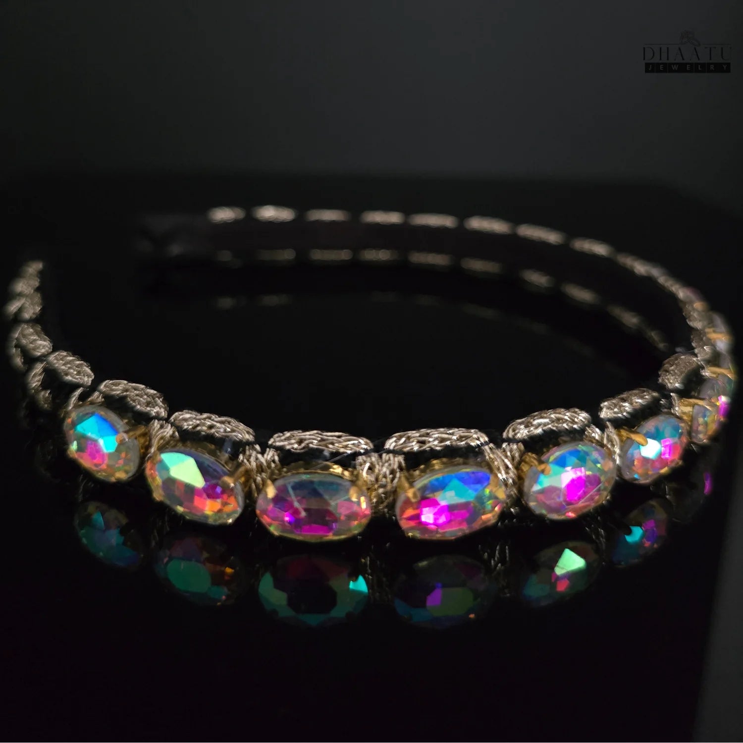 Full view of a Western headband showcasing iridescent crystals and golden weaving, with a reflective black surface below.