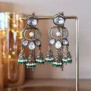 Stunning Kundan Jhumka earrings with bright green and white pearl bead drops, displayed on a gold jewelry stand.



