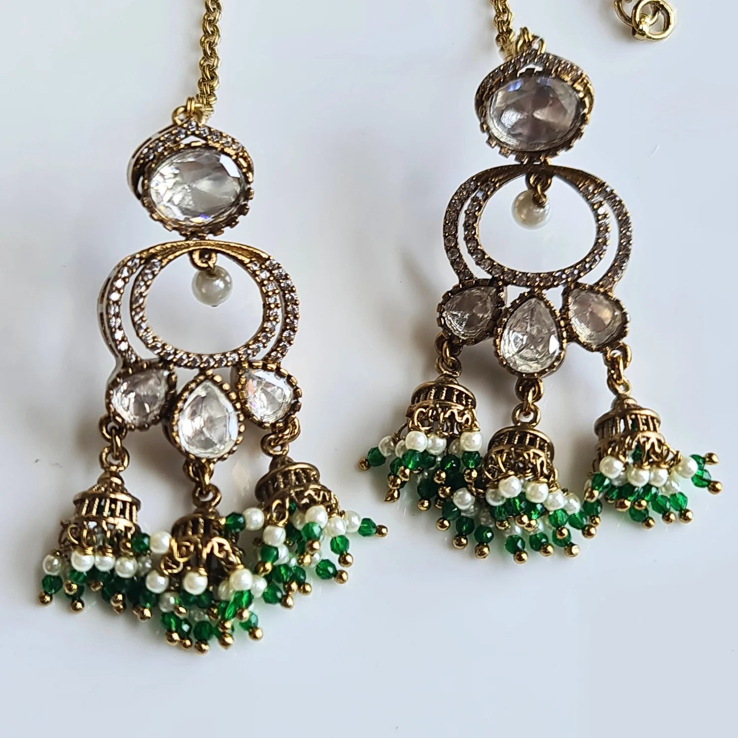 Close-up of ornate Kundan Jhumka earrings with rich green and white pearl bead drops and a delicate ear chain.



